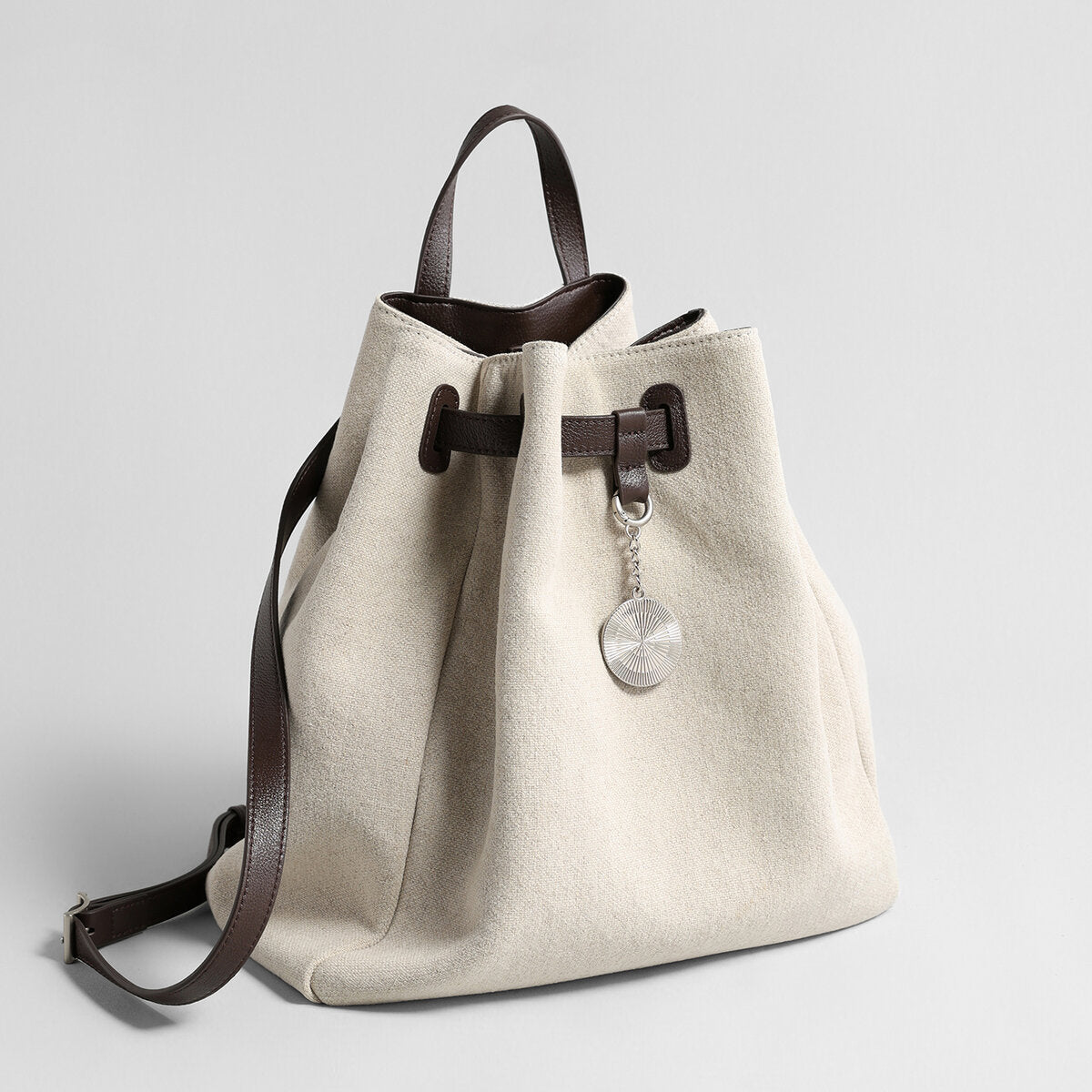 Canvas & Leather Drawstring Bucket Backpack – Convertible Daypack with Sunburst Charm